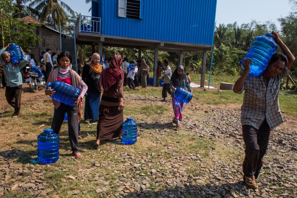Villagers carrying recently purchased water bottles away from the treatment plant.